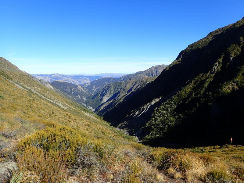 view down a green river valley with mountains on both sides